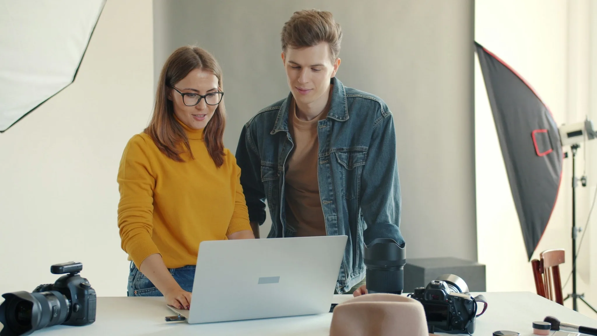Two people reviewing work beside a laptop in a studio.
